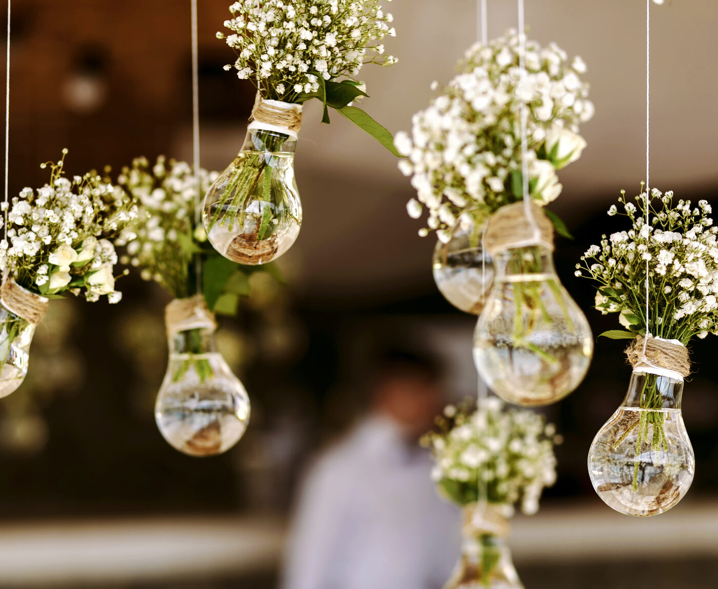 Glass bulb vases of white flowers hanging on strings