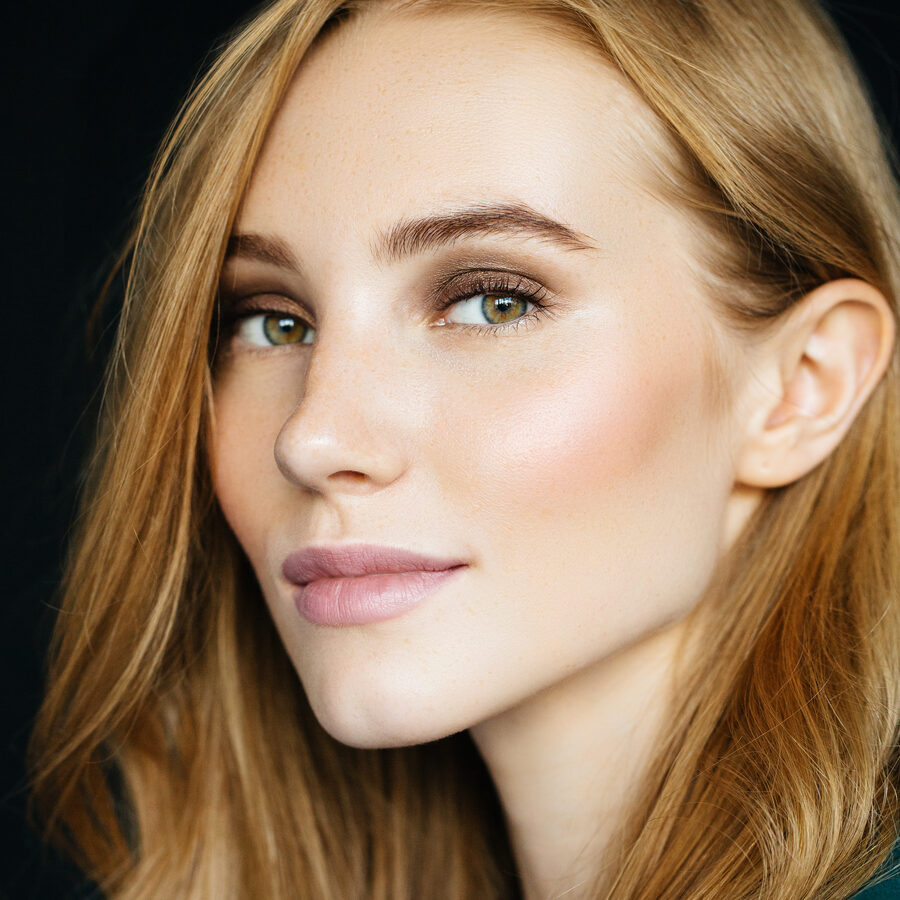 A woman with clear, luminous skin, turned towards soft side light